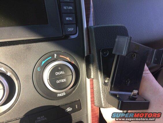 Car dashboard with climate control knobs and a phone mount.