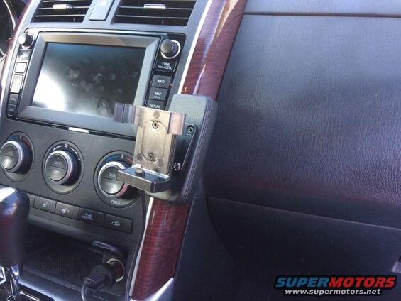 Car dashboard with phone mount, infotainment screen, and climate controls.
