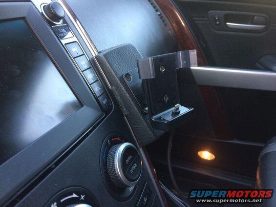 Car dashboard with phone holder mounted near infotainment screen and climate controls.