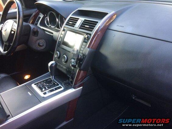 Interior of a Mazda CX-9 showing dashboard, steering wheel, gear shifter, and center console with phone mount.
