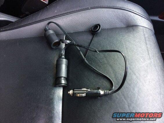 Black car cigarette lighter splitter with two sockets on a black leather car seat.