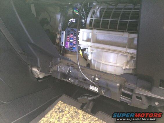 Vehicle dashboard interior showing fuse box and HVAC system components.
