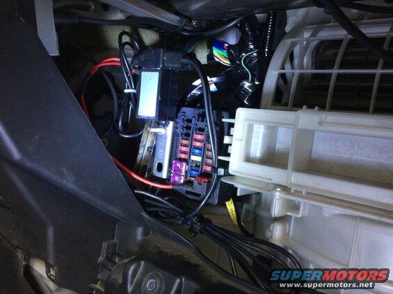 Close-up of a vehicle's interior fuse box and wiring installation.