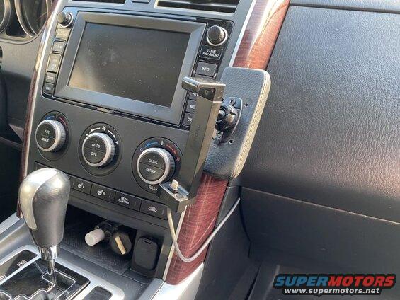 Interior dashboard view of a vehicle with climate controls, gear shifter, and phone mount.