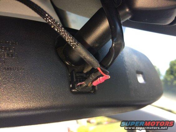 Close-up of vehicle rearview mirror wiring with exposed red and black wires.
