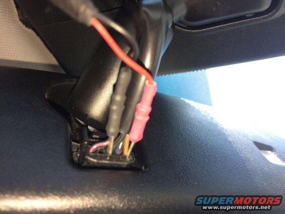 Close-up of vehicle interior wiring harness with multiple colored wires and connectors.