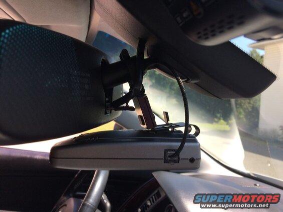 Radar detector and dashcam mounted on rearview mirror inside a car.