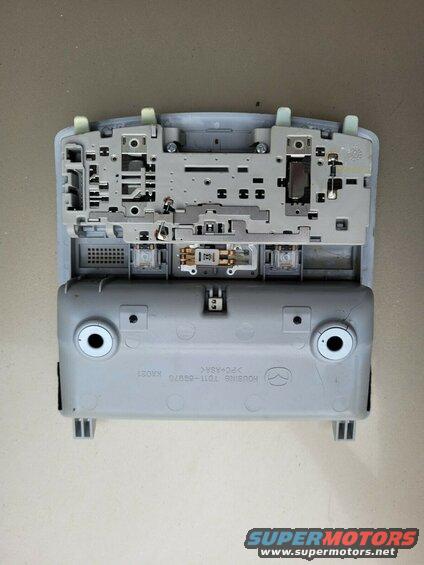Disassembled interior light housing for a Mazda CX-9, showing gray plastic and electrical components.