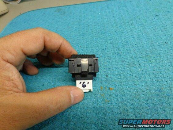 Black electrical switch component with a white label "6."