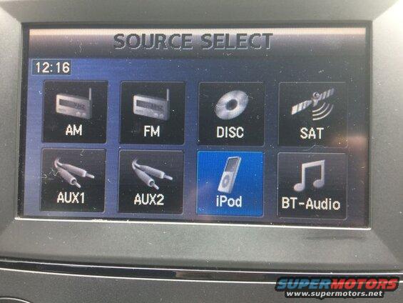 Car infotainment screen showing source select menu with AM, FM, DISC, SAT, AUX1, AUX2, iPod, and BT-Audio options.