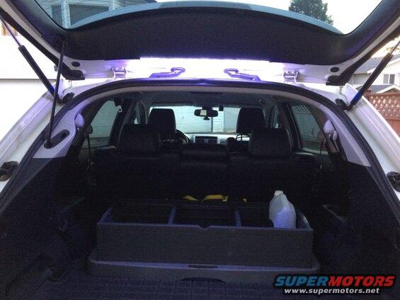 Interior of a white SUV with the rear hatch open, showing cargo area and blue LED lights.