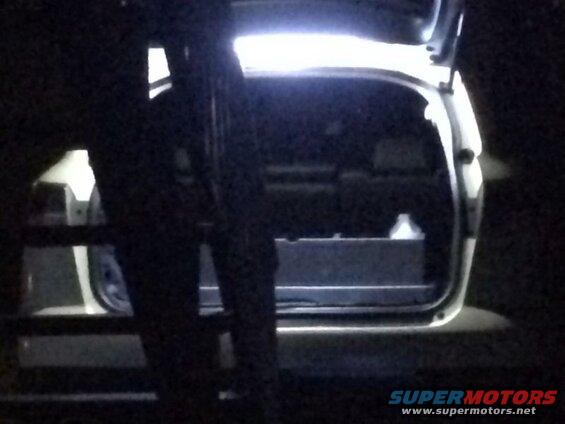 Rear view of an open white SUV hatch at night with cargo inside.