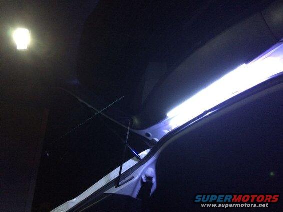 Interior of a vehicle with LED light strip and overhead light, rear hatch open.