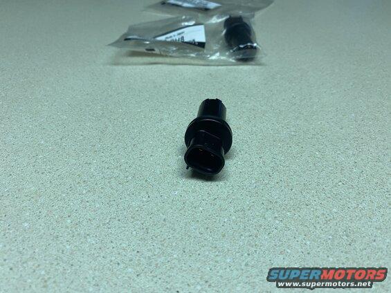 Black automotive electrical connector on a speckled surface.