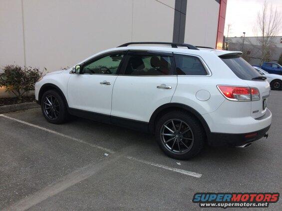Side view of a white 2009 Mazda CX-9 SUV with dark grey wheels and roof rack.