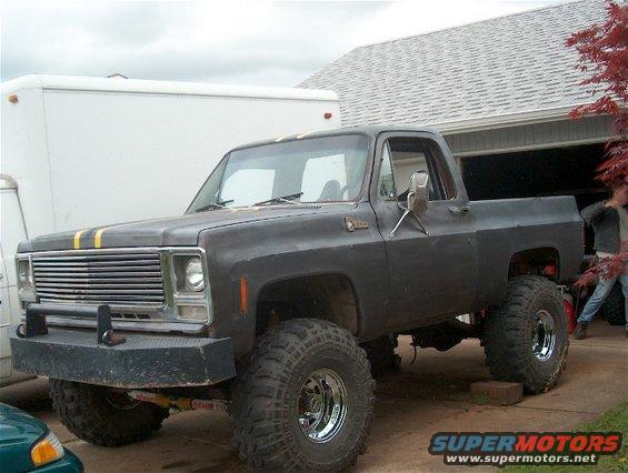 Dark gray lifted pickup truck with yellow racing stripes and aftermarket bumper