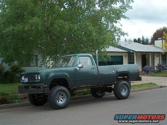 Green lifted pickup truck parked on a residential street. Exhaust stack visible behind the cab