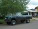 1979 Ford Bronco - This lifted pickup truck is parked on the side of a street in front of a house.