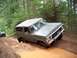 1979 Ford Bronco - A gray 1978 Ford Bronco navigates a muddy trail in a forest, with another vehicle visible in the background.