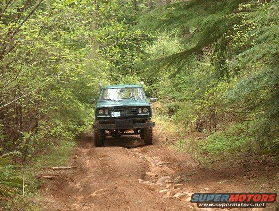 Green 1979 Ford Bronco on a muddy forest road