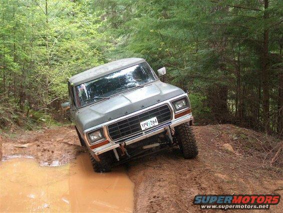 1979 Ford Bronco driving through mud on a wooded trail