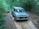 1979 Ford Bronco - A gray 1978 Ford Bronco navigates a muddy trail in a forest, with another vehicle following behind.