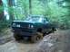 1979 Ford Bronco - This pickup truck is navigating a muddy trail in a wooded area, with a person visible in the background.