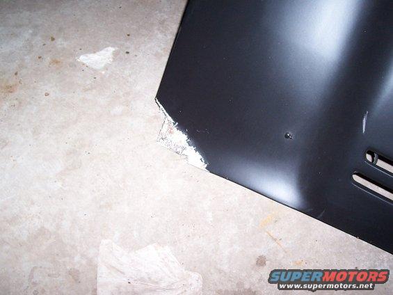 Black car panel with chipped white primer on the corner, showing two horizontal vents