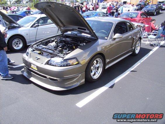 Tan 2002 Ford Mustang GT with hood open, showing engine and custom front bumper