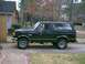 1988 Ford Bronco - A black Ford Bronco is parked on a suburban driveway with trees in the background.