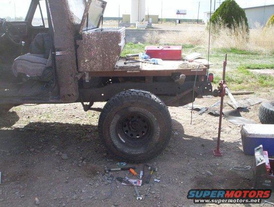 1978 Ford Bronco with a flatbed conversion, covered in mud, with a jack and tools nearby