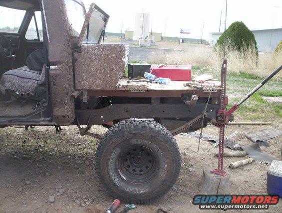 Mud-covered truck bed with Hi-Lift jack and toolbox