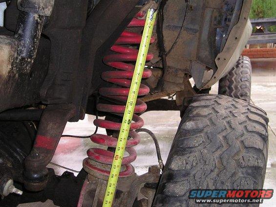 Close-up of red coil spring and suspension components with tape measure