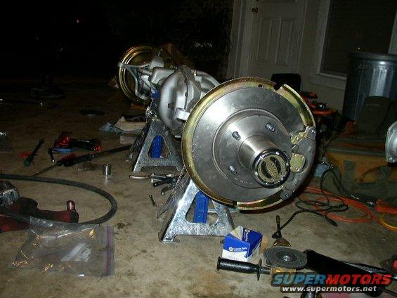 1995 Ford Bronco rear axle assembly with brake components on jack stands, tools scattered around