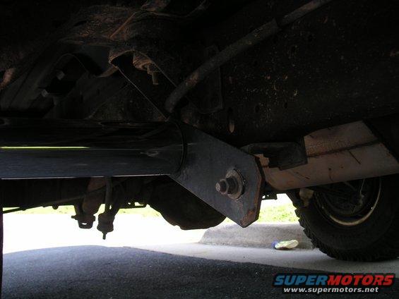 Underside of vehicle showing frame, suspension, and step bars. Tire visible on right