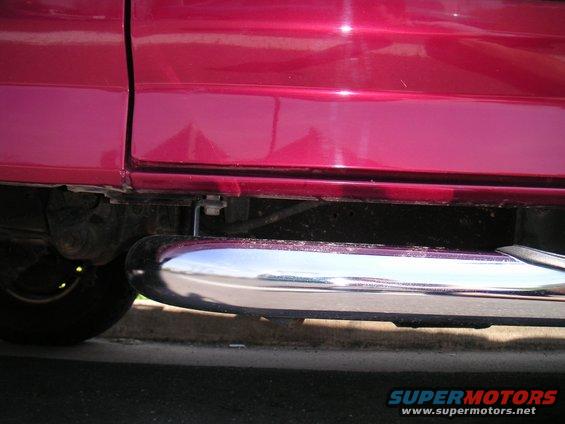 Red vehicle side panel with chrome step bar below. Tire visible on left