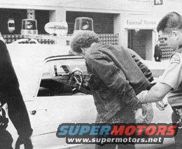 Side view of a police car with a man being arrested