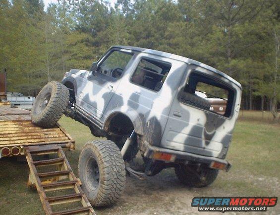 Camouflaged Suzuki Samurai on a trailer ramp