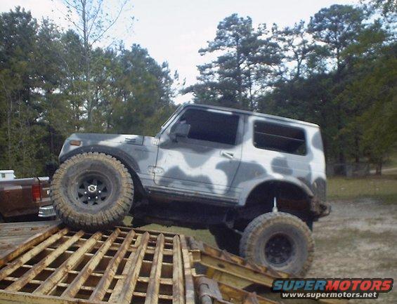 Camouflaged off-road vehicle with large tires on a yellow ramp