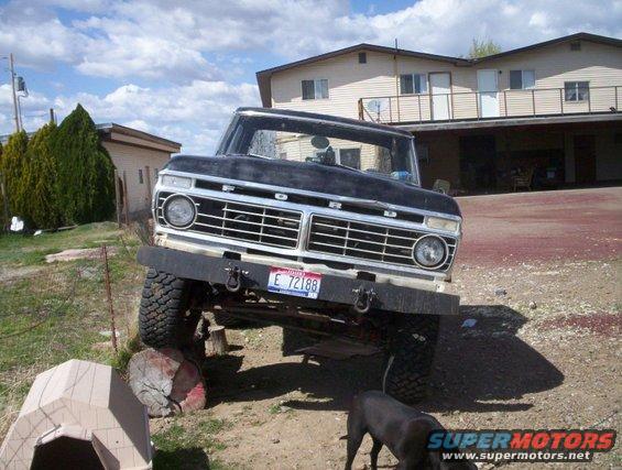 Black Ford F-Series truck with a custom bumper and off-road tires, parked in a dirt lot