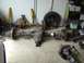 1993 Ford Bronco - Vehicle axles and shocks are stored on a garage floor next to a spare tire and battery display.