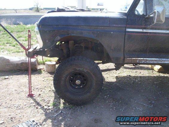 1978 Ford Bronco front fender, tire, and Hi-Lift jack attached to frame
