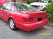 1995 Ford Taurus - A red 1995 Ford Taurus is shown from the rear, with a white van visible in the background.