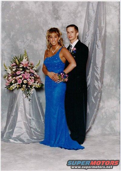 Woman in blue dress and man in suit pose for prom photo