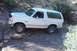 1995 Ford Bronco - White 1995 Ford Bronco is shown off-roading over rocks on a dirt path.