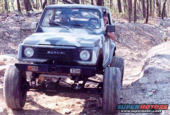 Suzuki Samurai with large tires driving on a rocky trail