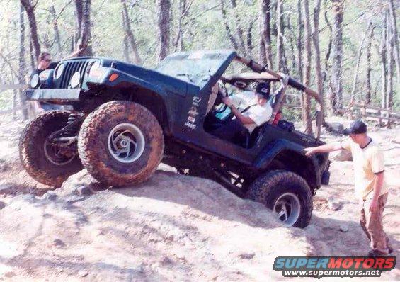 Green Jeep Wrangler TJ climbing rocks with two people inside and one person outside