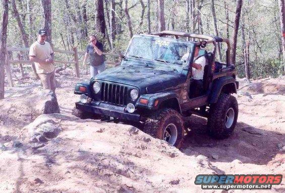 Dark green Jeep Wrangler TJ navigating rocky terrain