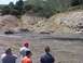 2000 Ford F-450 - Trucks navigate a muddy terrain in a scenic, hilly landscape.