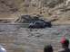 2000 Ford F-450 - Off-road vehicles are stuck in thick mud, with spectators observing the scene.